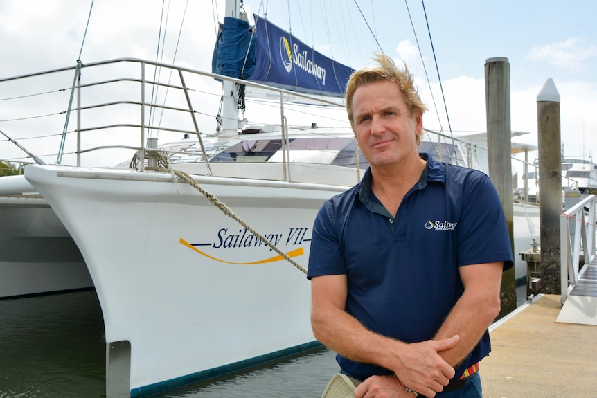 Steve Edmondson, propietario y operador de Sailaway, se encuentra junto a su barco en el puerto deportivo.