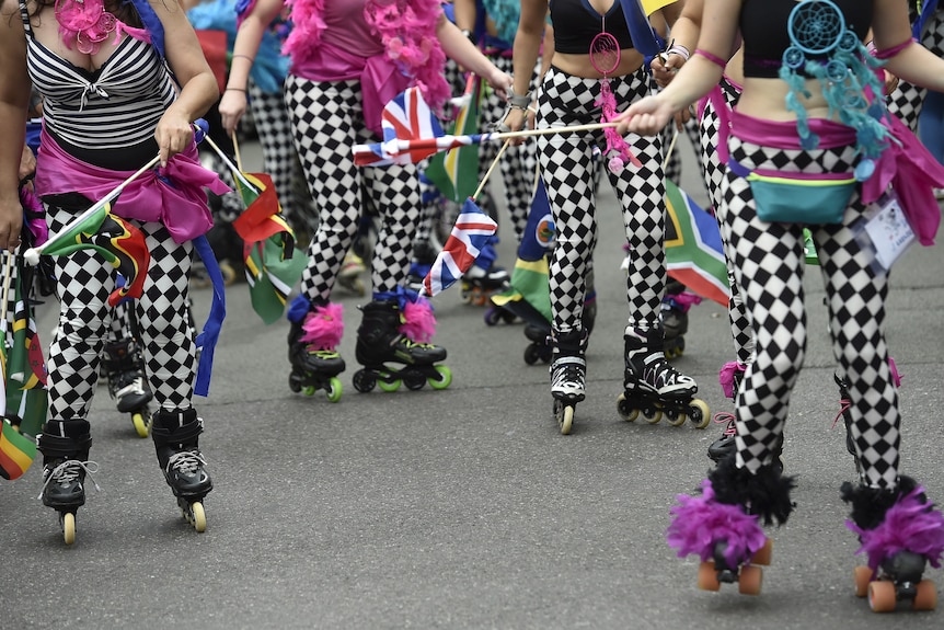 The legs of four females who are all wearing black and white patterned tights and rollerblades on their feet.