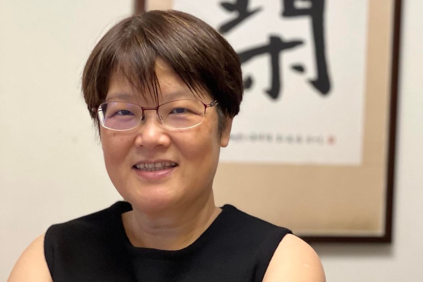 A Taiwanese woman with short hair and glasses smiling at camera.