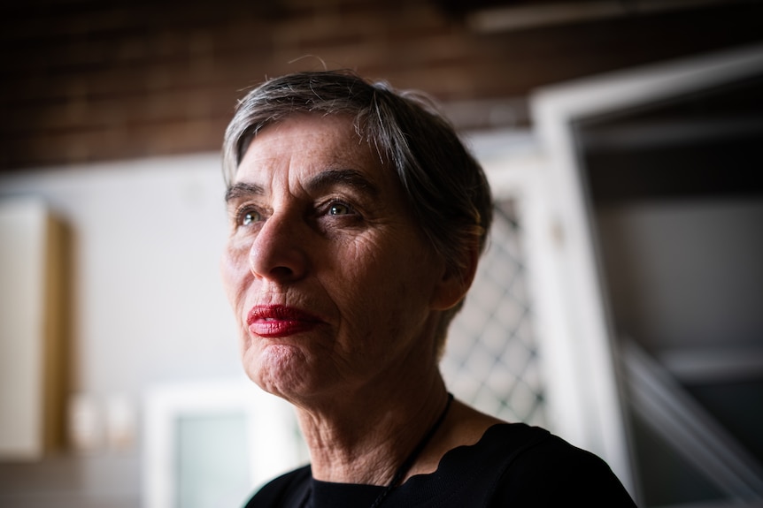 A close photo taken from a low angle of a woman with short hair wearing a black top and red lipstick