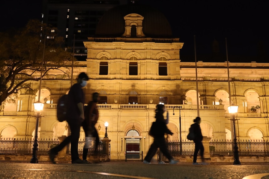 People walking past Queensland Parliament at night