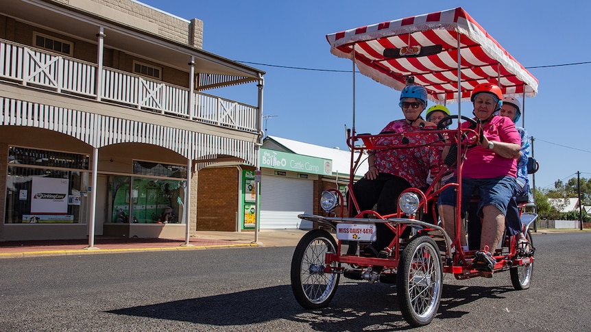 Four riders sit on a bike in the main street of Charleville