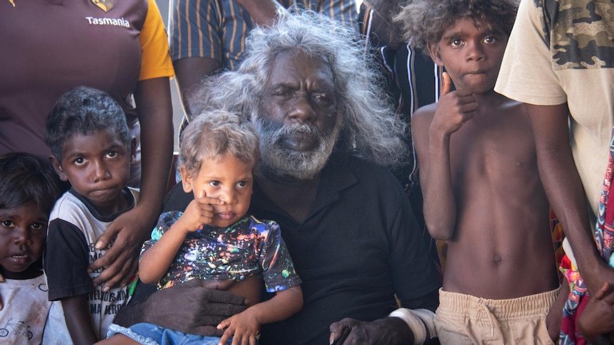 A man sits with his young grandchildren.