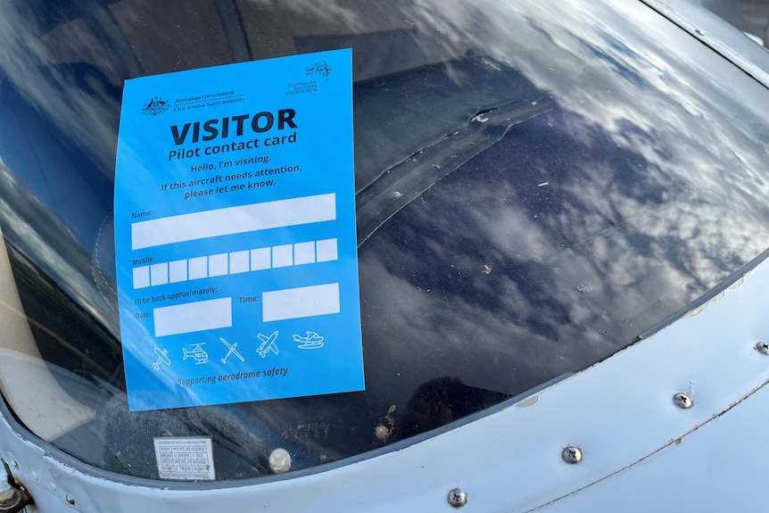 A blue visitor contact information card in the windshield of a light aircraft.