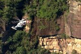 A helicopter next to a rock face