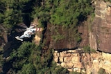 A helicopter next to a rock face