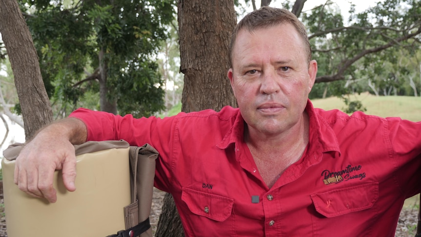 Dan Fischer stands outside in front of some trees with a swag.