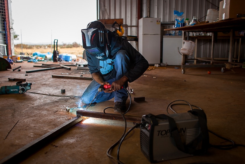 ma with welding shield welding metal frame on the workshop