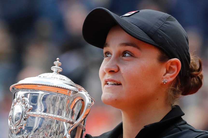 A tennis player stands with the trophy after winning the French Open women's singles final.