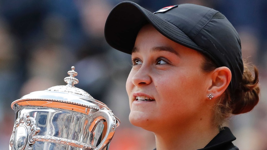 A tennis player stands with the trophy after winning the French Open women's singles final.