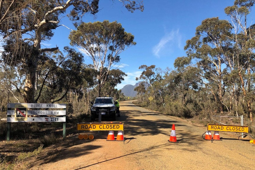 An emergency vehicle blocks the main road to bluff knoll with signs and traffic cones.