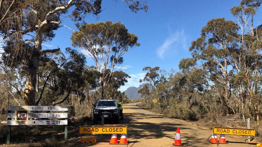 An emergency vehicle blocks the main road to bluff knoll with signs and traffic cones.
