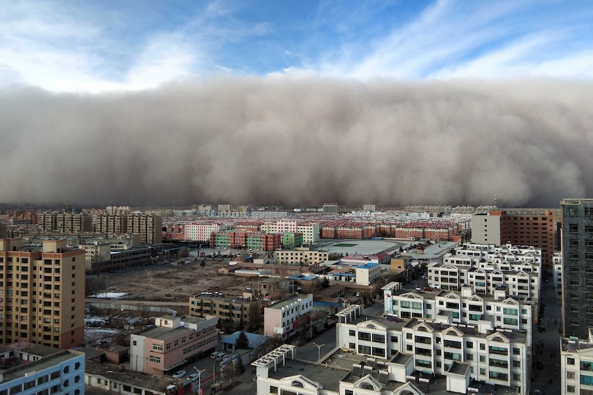 A huge dust storm approaches a city in China.