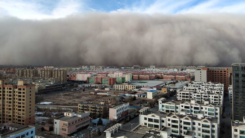 A huge dust storm approaches a city in China.