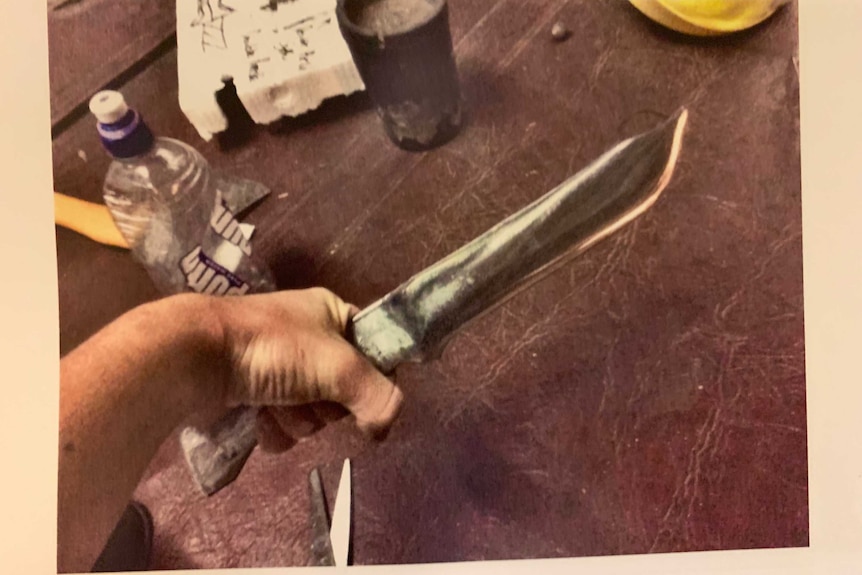 A man's hand holding a homemade knife