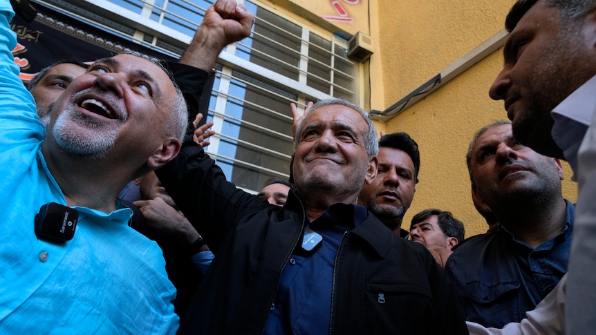 Masoud Pezeshkian raises his fist in the air in celebration.
