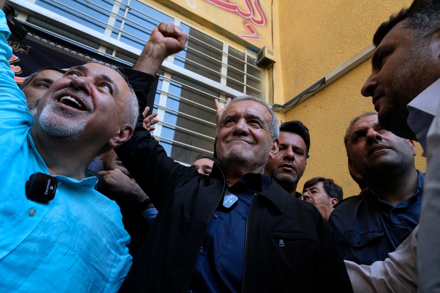 Masoud Pezeshkian raises his fist in the air in celebration.