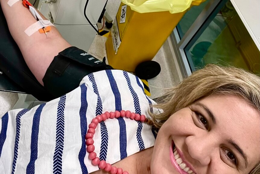 Kate sits in a hospital chair and is donating blood for a good cause.