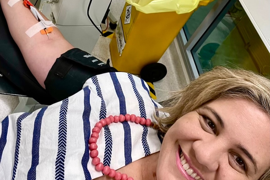 Kate sits in a hospital chair and is donating blood for a good cause.