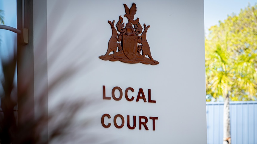 A large white sign showing a coat of arms and the words "local court".