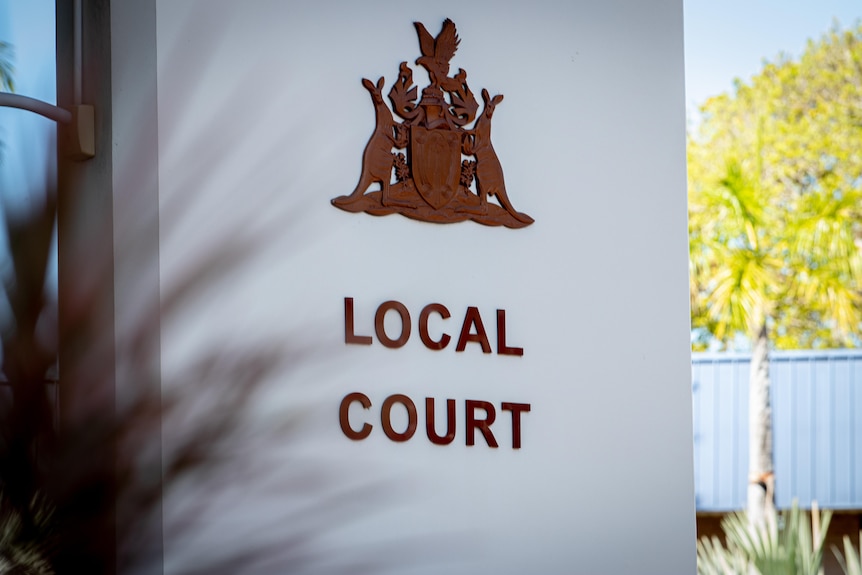 A large white sign showing a coat of arms and the words "local court".