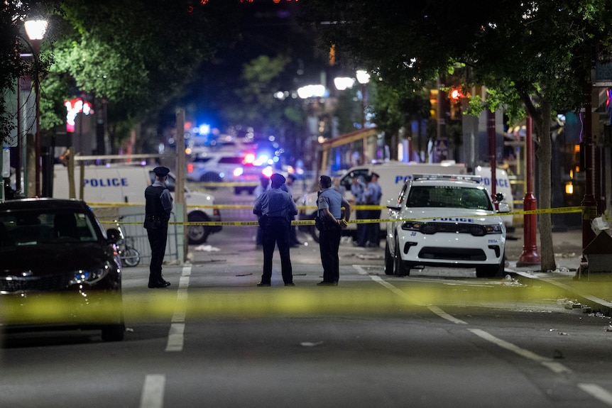 Philadelphia Police officers and detectives look over evidence at the scene of a shooting.