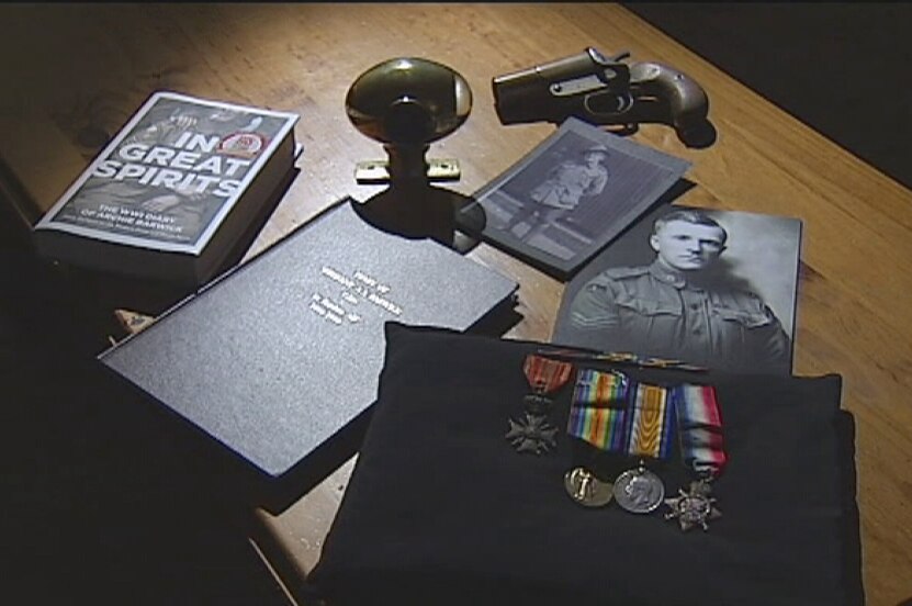 On a table lies a photo of ANZAC Barwick, a gun, a diary and medals collected by his family