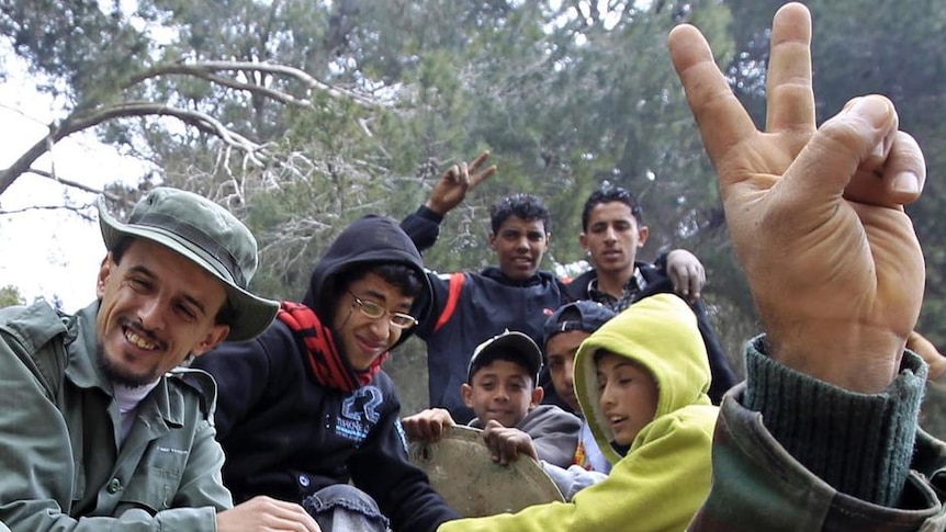 A man fires his pistol into the air as he celebrates with others in Libya