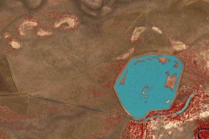 Satellite image of a full dam in brown countryside