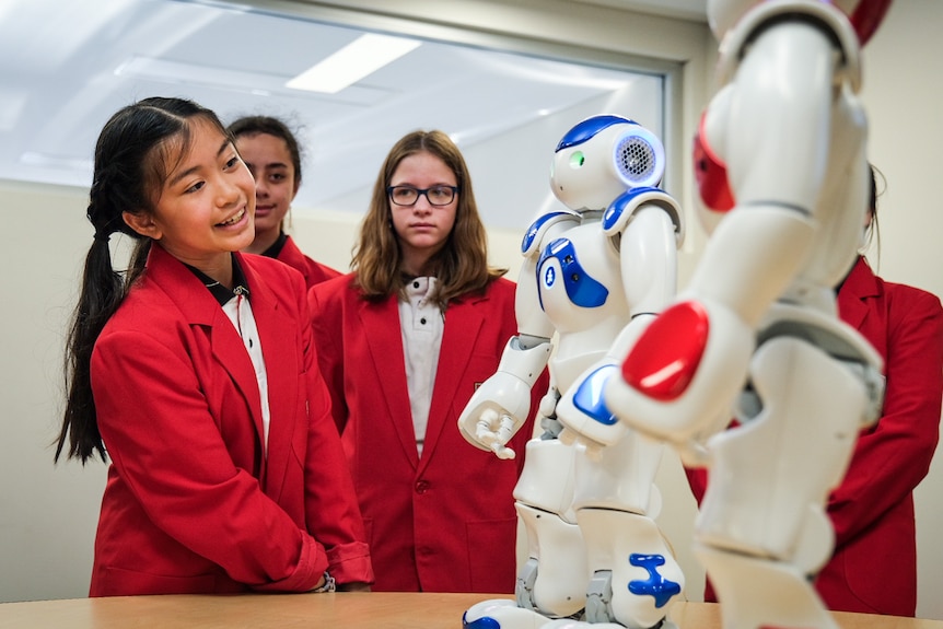 a group of young female students talk to robots