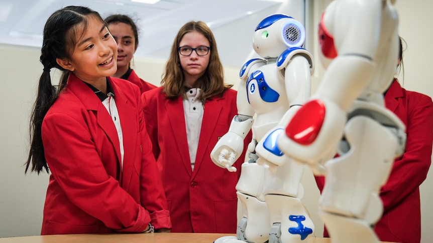 a group of young female students talk to robots