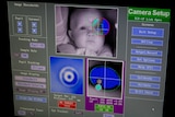 A computer screen shows footage of a baby's face being monitored.