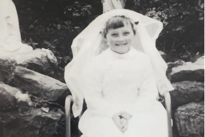 A black and white photo of a girl in a white dress