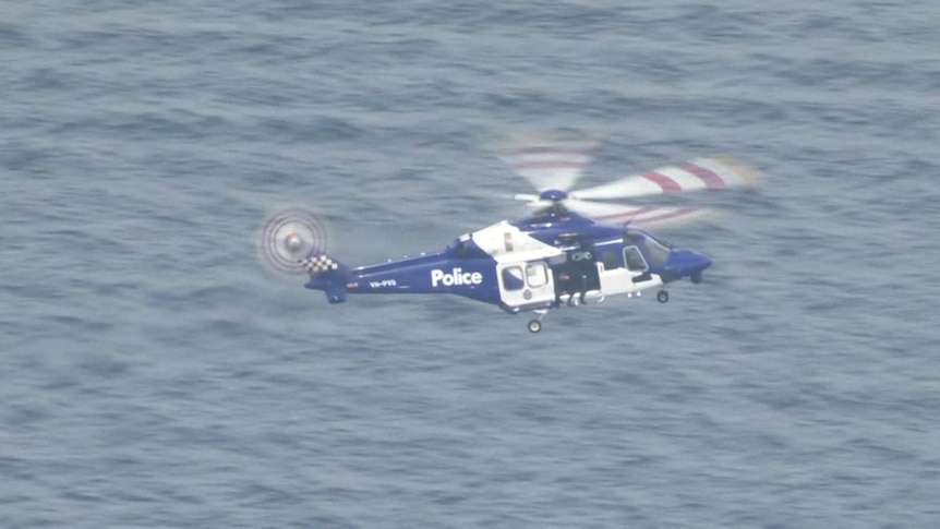 A police helicopter flying above the sea.