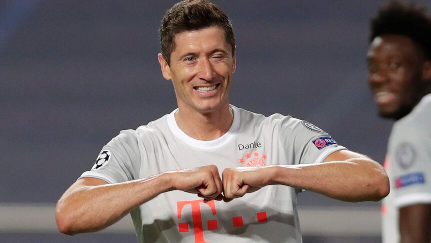 Smiling, Robert Lewandowski celebrates scoring a goal for Bayern Munich by winking and bumping his fists together