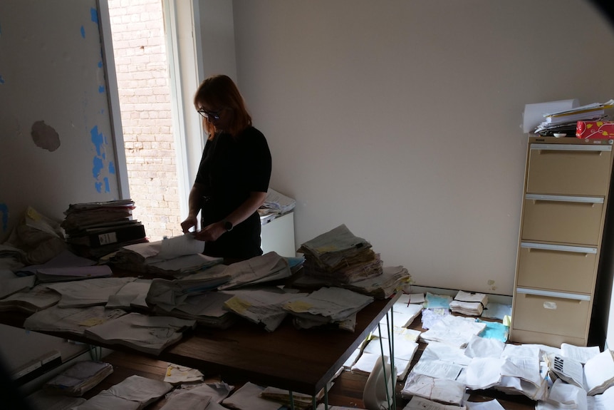 A woman silhouetted parses through legal documents  