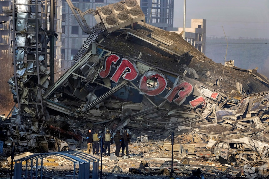 People examine the damage after shelling of a shopping centre, in Kyiv, Ukraine, Monday, March 21, 2022.