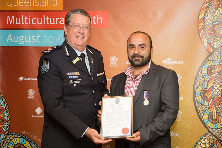 Iraqi refugee Teimoor Amin (right) receives a Queensland Police Bravery Medal