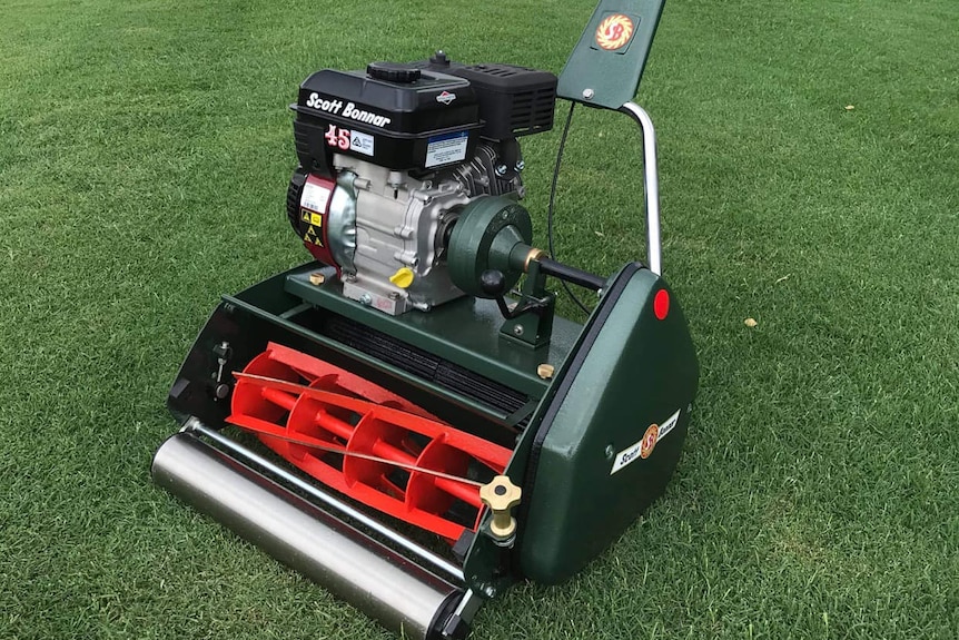 A restored cylinder mower on a front lawn.