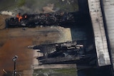 Part of a warehouse burns after a chemical fire. The building is charred and smouldering