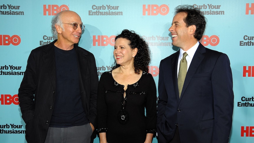 Larry David, Susie Essman and Jerry Seinfeld in front of wallpaper with logo "curb your enthusiasm" 