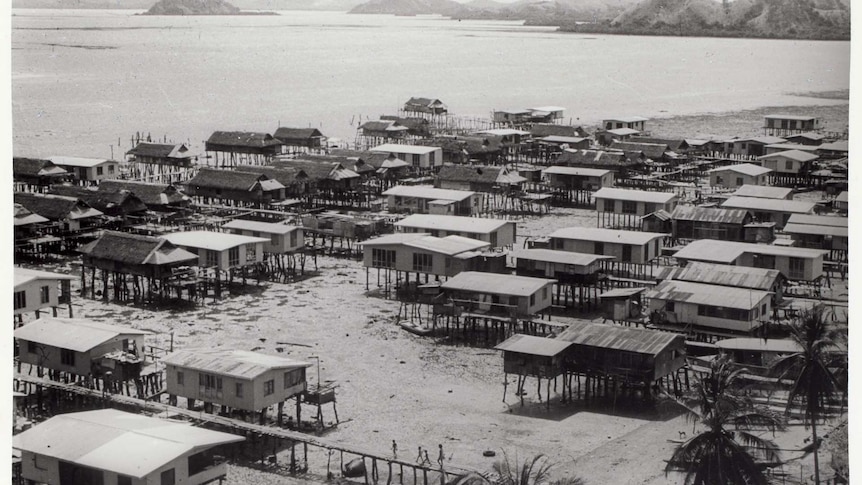 Low tide on a coastal scene, section of about 50 houses all built upon stilts about 2-3 metres in the air.