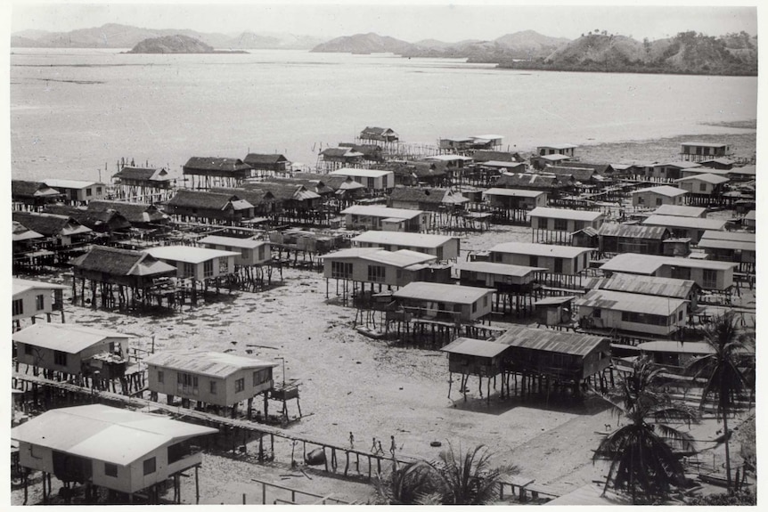 Low tide on a coastal scene, section of about 50 houses all built upon stilts about 2-3 metres in the air.