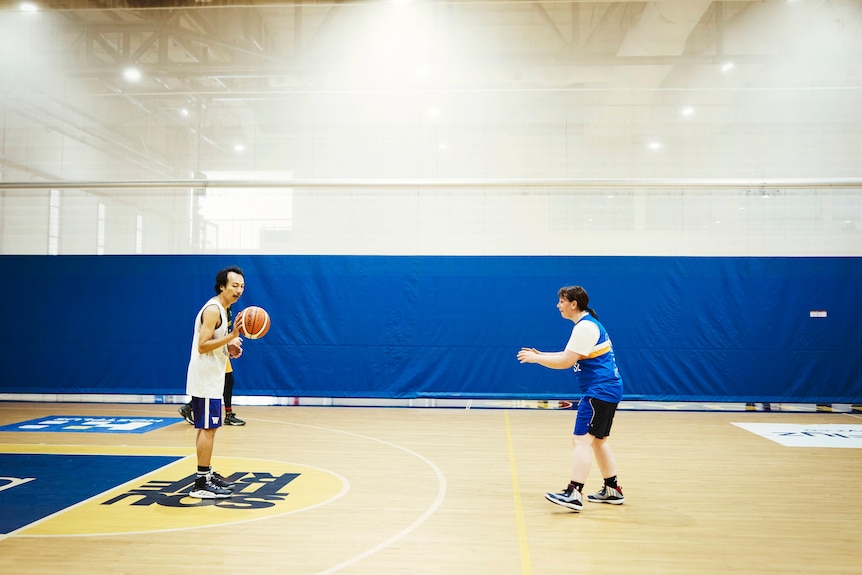 Two people are on a basketball court, playing a social game.