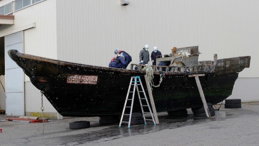 Coast guard officials investigating a wooden boat in Japan.