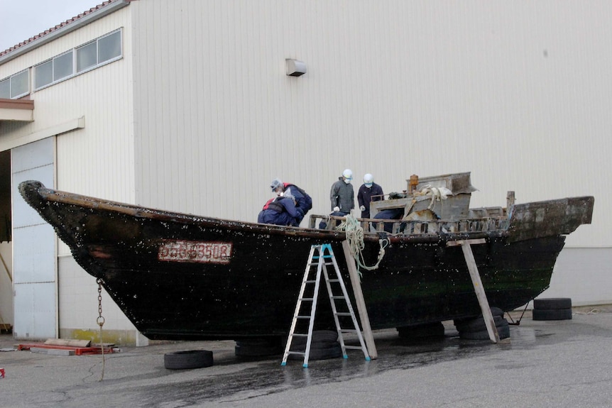 Coast guard officials investigating a wooden boat in Japan.