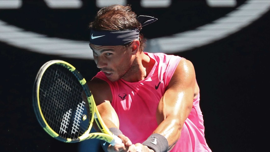 A pink-shirted tennis player grimaces as he hits a return during the Australian Open.