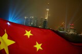 The Chinese flag flies in the evening, with Shanghai's Pudong skyline in the background.