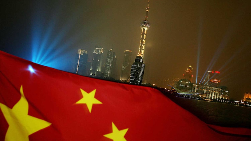The Chinese flag flies in the evening, with Shanghai's Pudong skyline in the background.