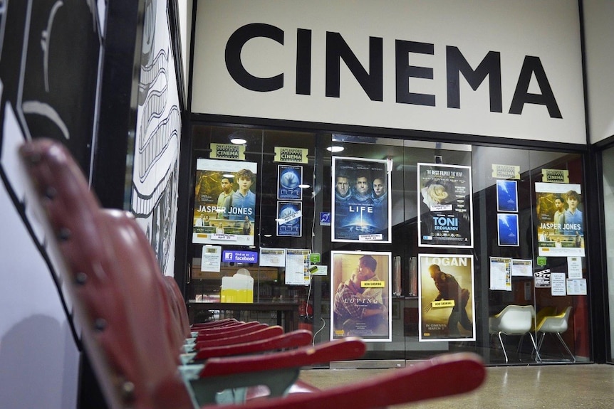 Movie posters adorn windows with the word, cinema, above it